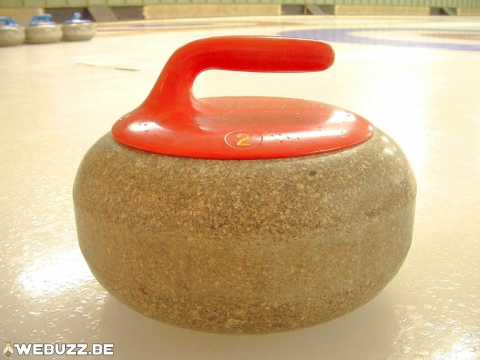 Pierre de curling en granit avec poignée rouge.